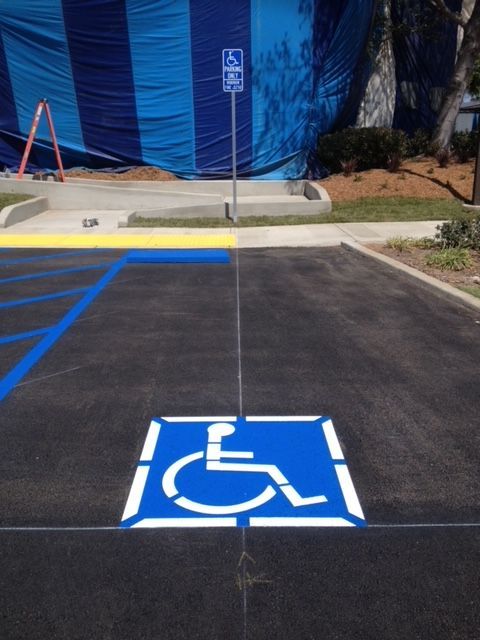 A handicap sign is painted in the middle of a parking lot