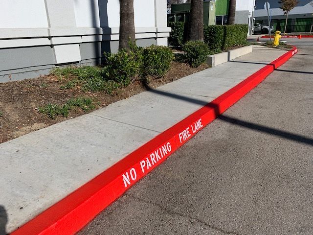 A red curb that says no parking fire lane