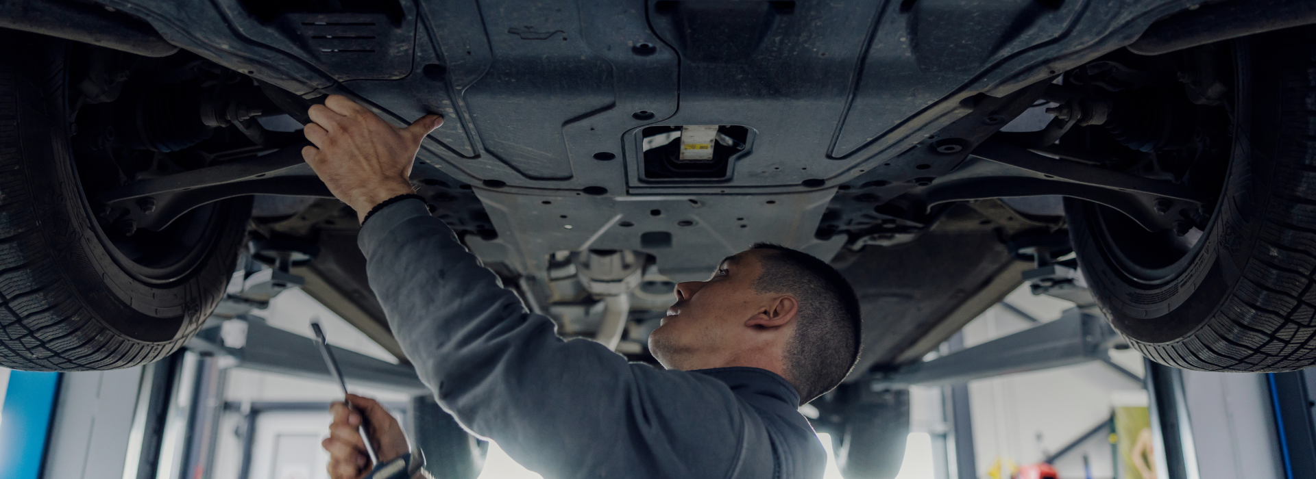 Technician working on bottom of car | AT Automotive