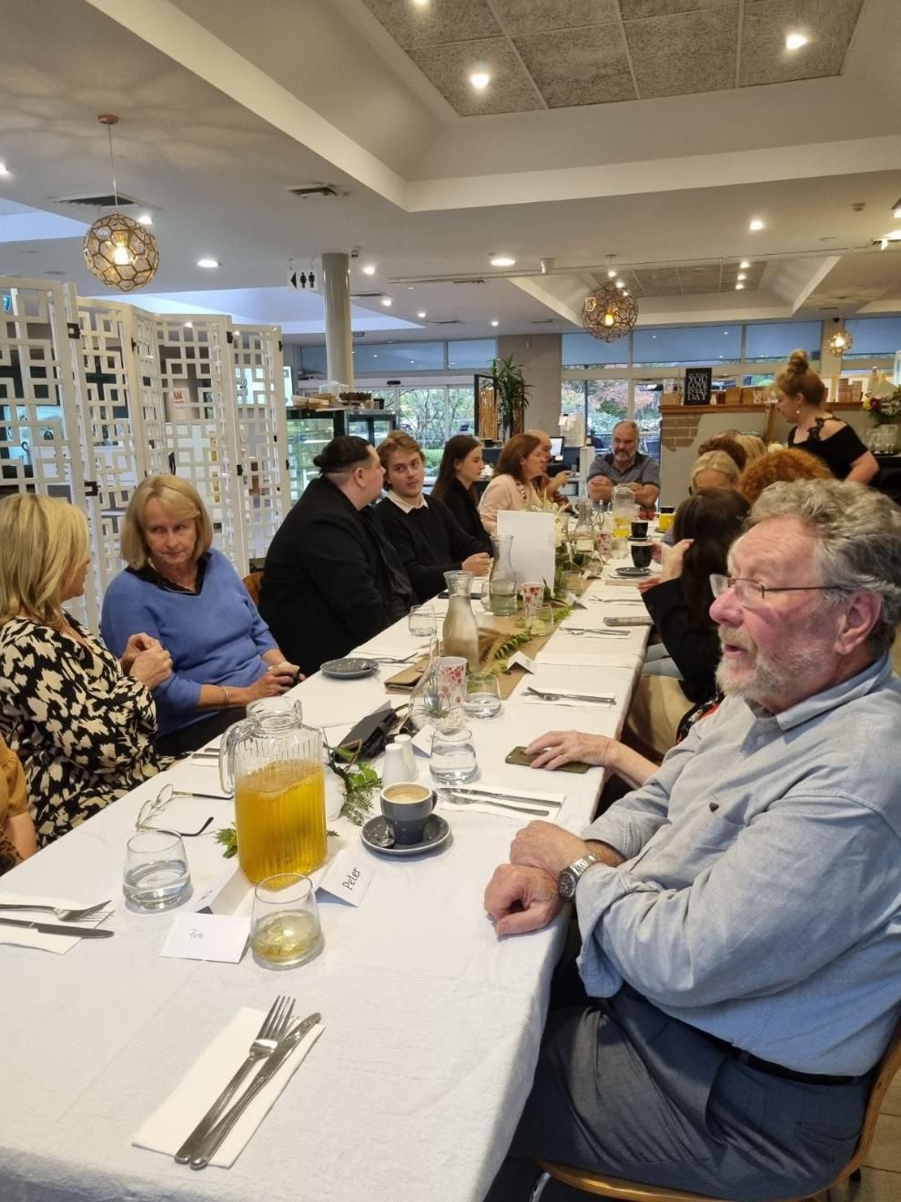 A Group Of People Are Sitting At A Long Table In A Restaurant — Top Point Café In East Gosford, NSW