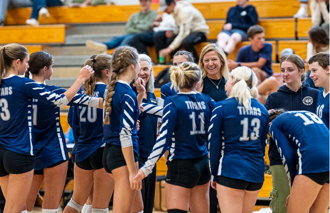 A group of volleyball players are huddled together in a gym.