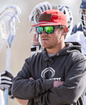 A man wearing sunglasses and a red hat is standing with his arms crossed