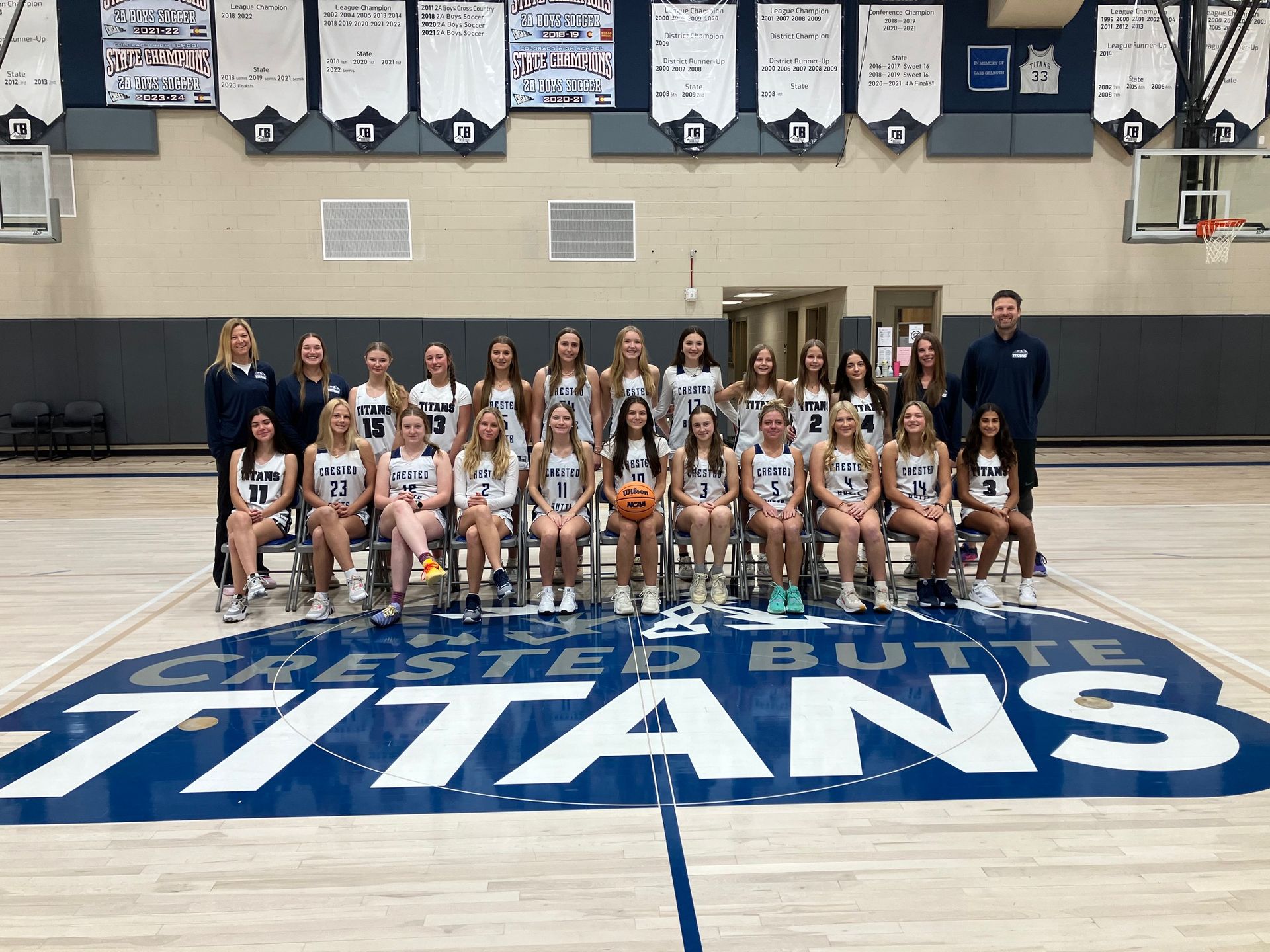 A group of girls are posing for a picture on a basketball court.