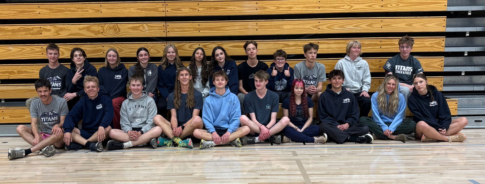 A large group of people are posing for a picture in front of a mountain.
