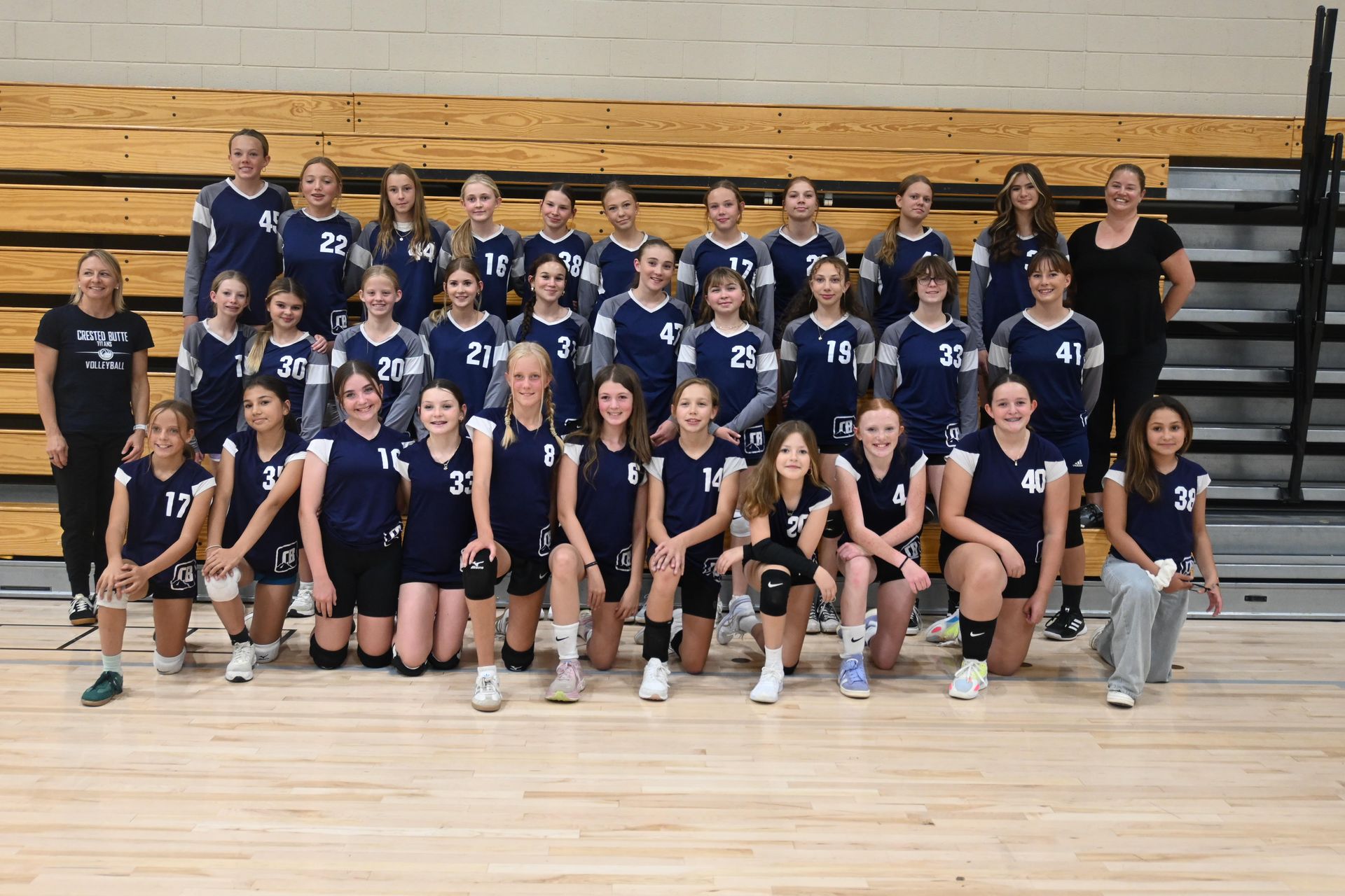 A group of young girls are posing for a picture with the word volleyball written in front of them
