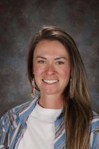 A woman in a blue and white striped shirt is smiling for the camera.