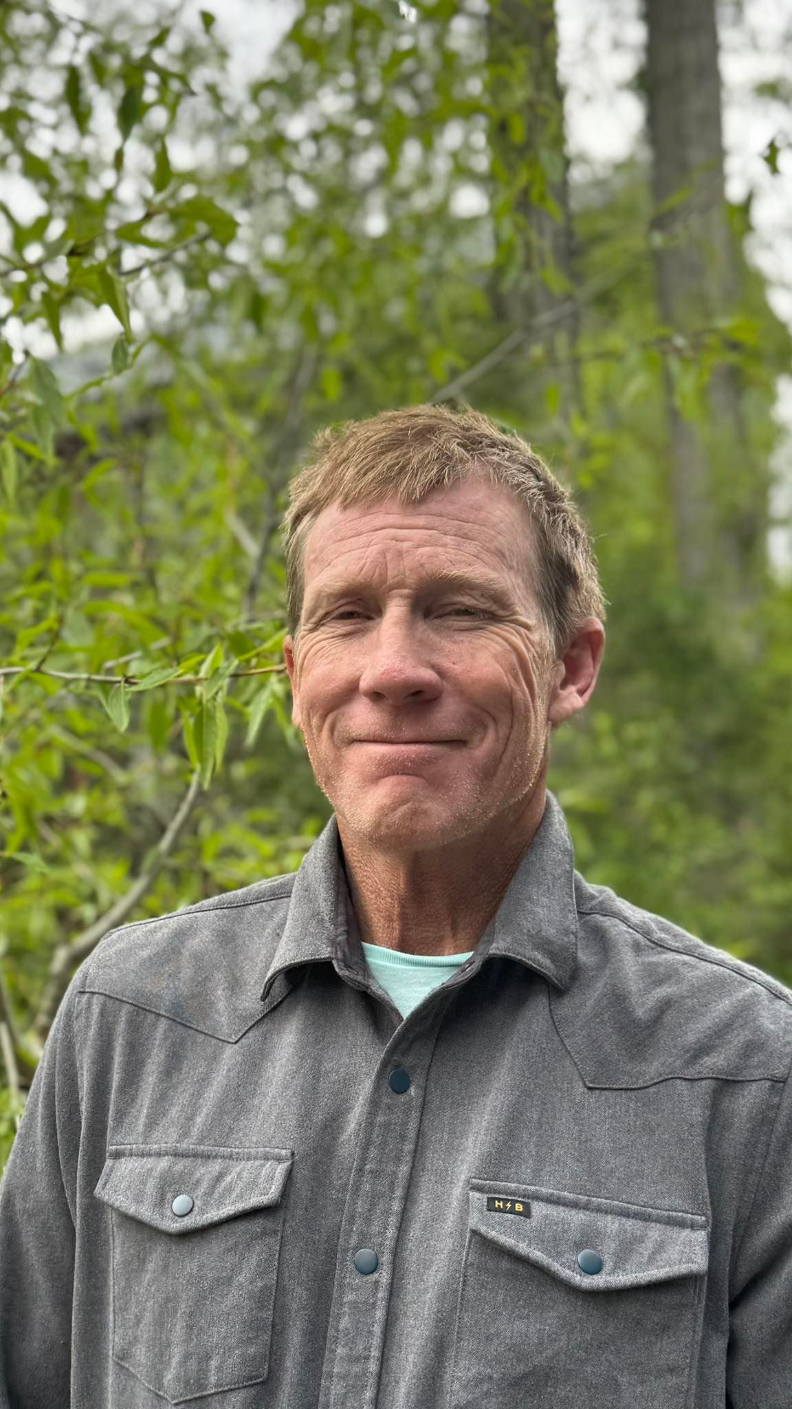 a man wearing a hat and sunglasses is smiling for the camera .