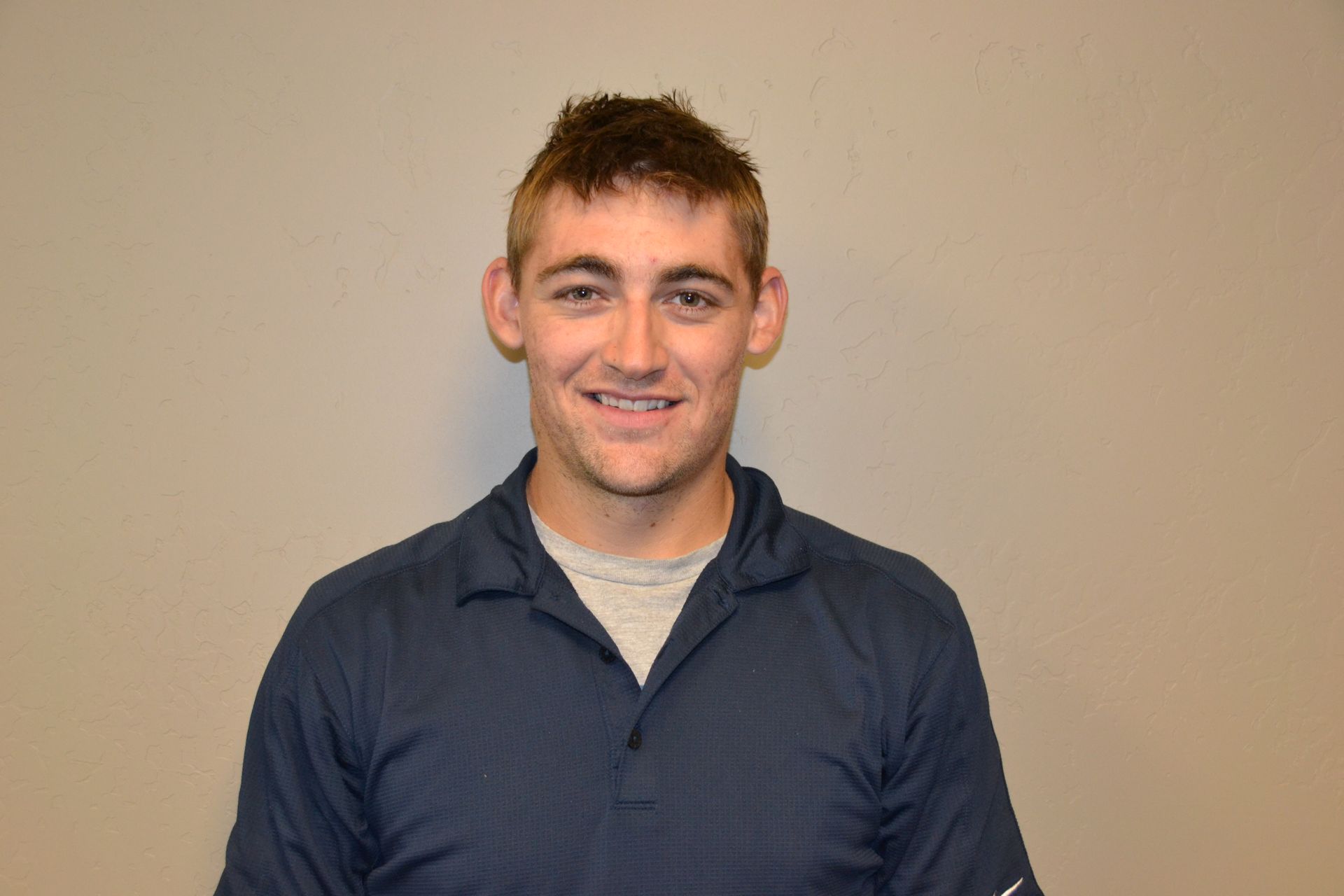 a young man in a blue shirt is smiling for the camera .