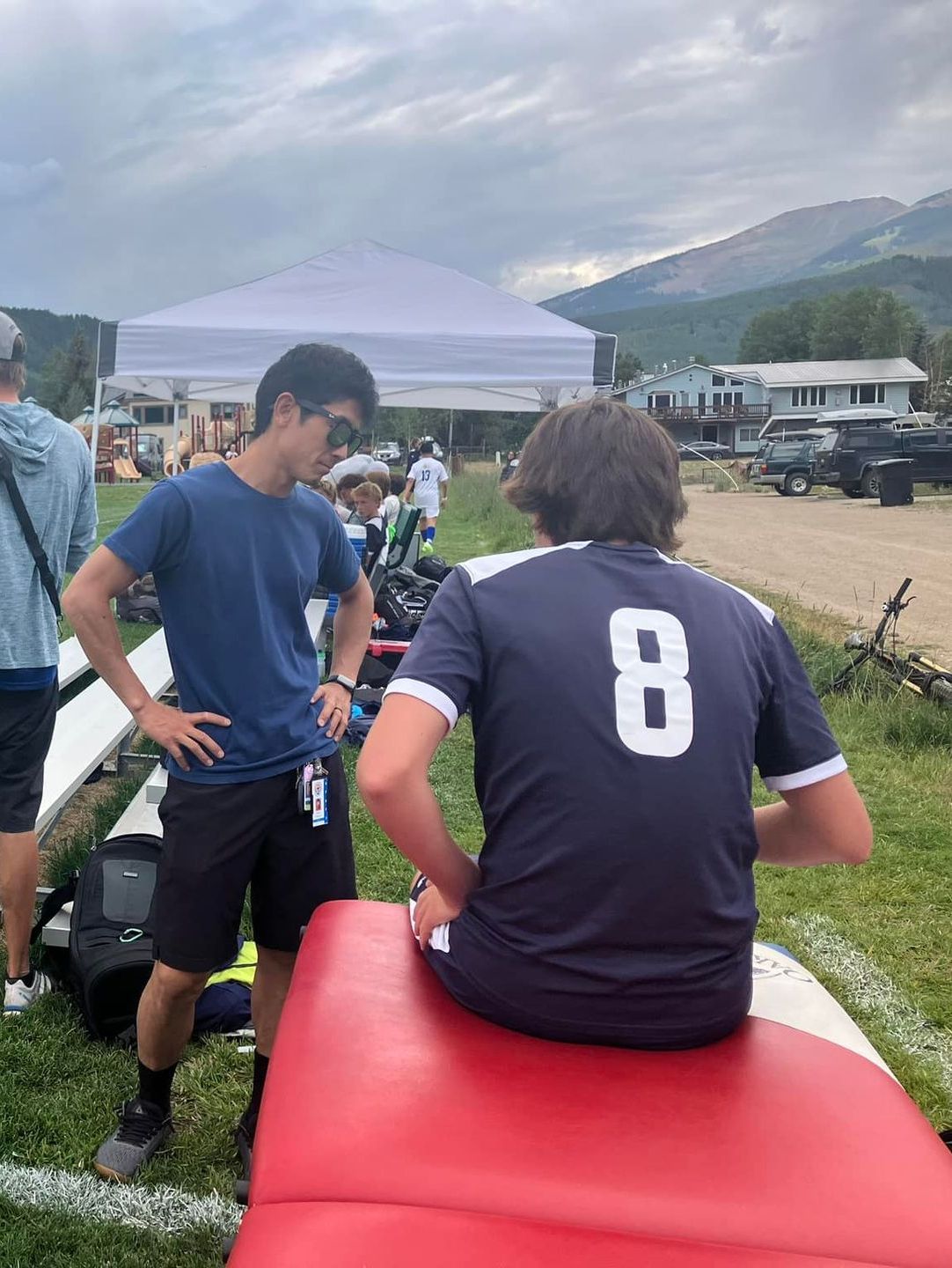 A man in a blue shirt with the number 8 on it is sitting on a red bench.