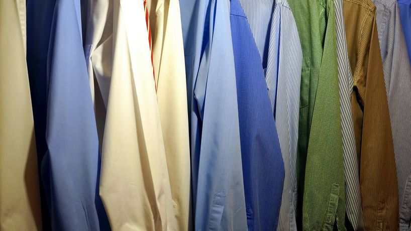 A row of shirts and ties are hanging on a rack.