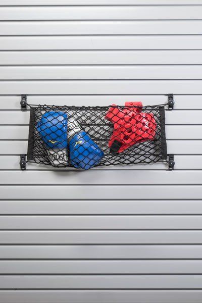 A pair of boxing gloves and a helmet are hanging on a mesh shelf on a wall.