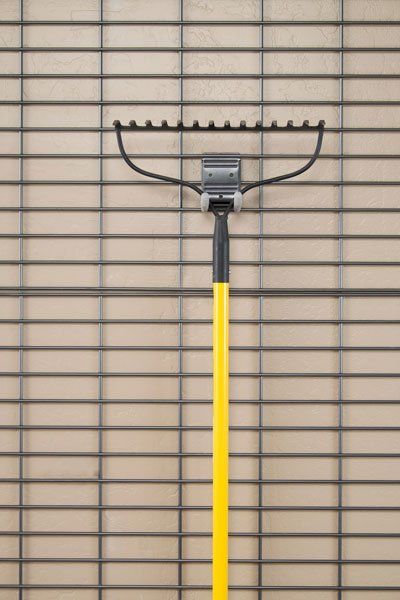 A yellow rake is hanging on a grid wall