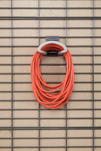 A hose is hanging on a wire rack on a wall.