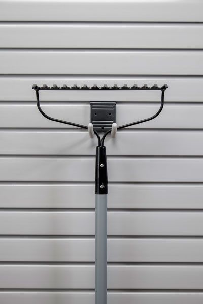 A rake is hanging on a hook on a wall.