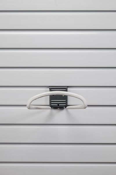 A white hook is hanging on a white wall.