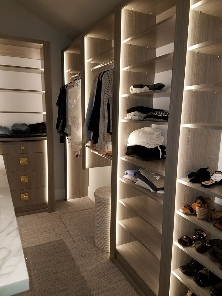 A walk in closet with lots of shelves and clothes on them