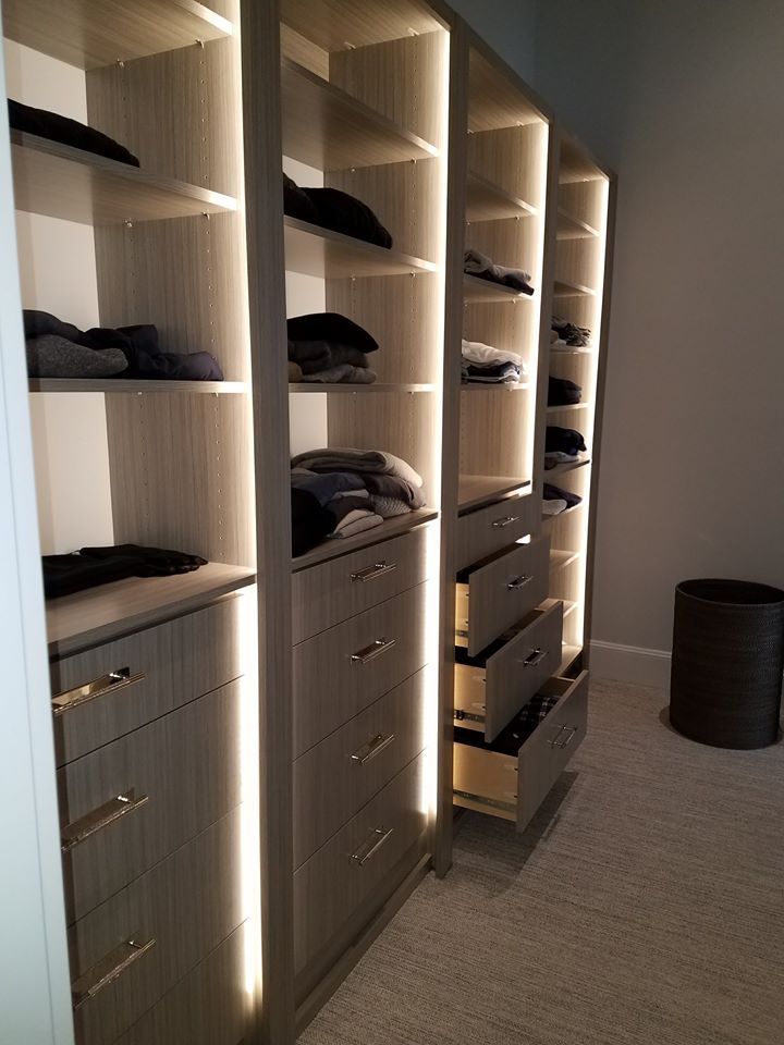 A walk in closet with lots of shelves and drawers