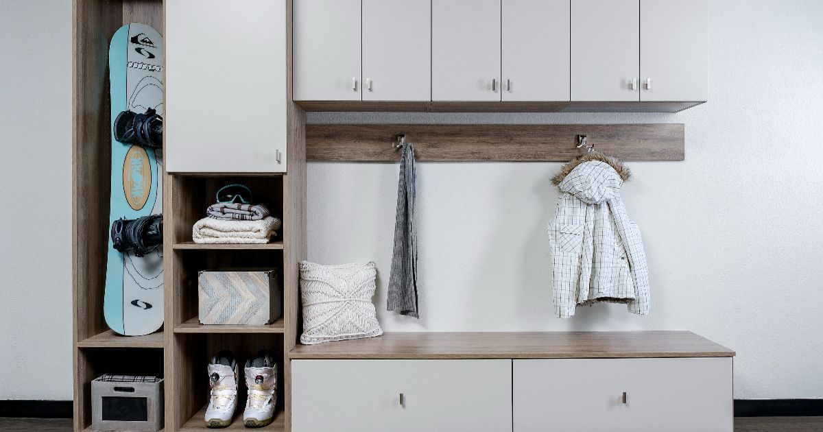A modern mudroom storage unit with a snowboard rack, open shelving, closed cupboards, a bench, and wall hooks for gear.