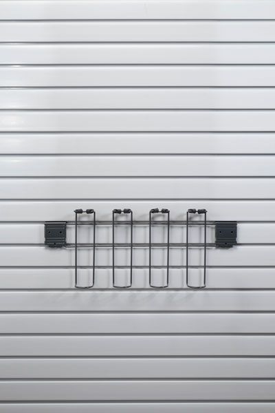 A metal rack is hanging on a white wall.