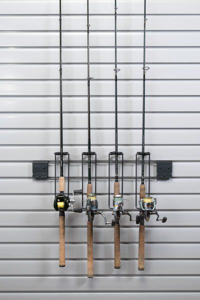 Four fishing rods are hanging on a rack on a wall.