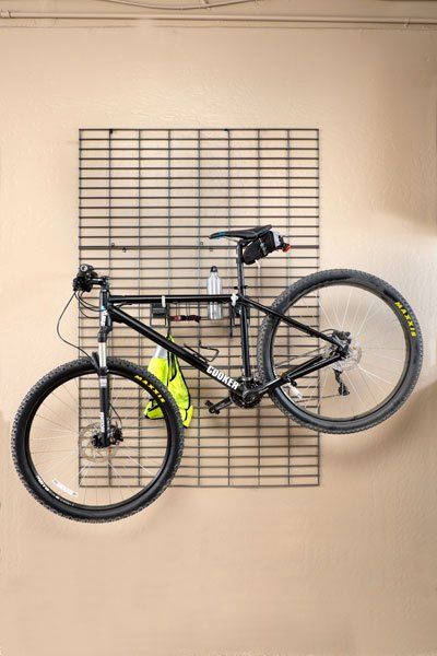 A bicycle is hanging on a wall in a garage.