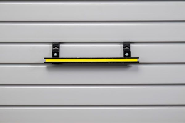 A yellow shelf is hanging on a white wall.