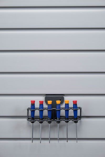 A bunch of screwdrivers are hanging on a rack on a wall.