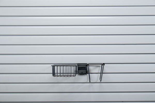 A black basket is hanging on a white wall.