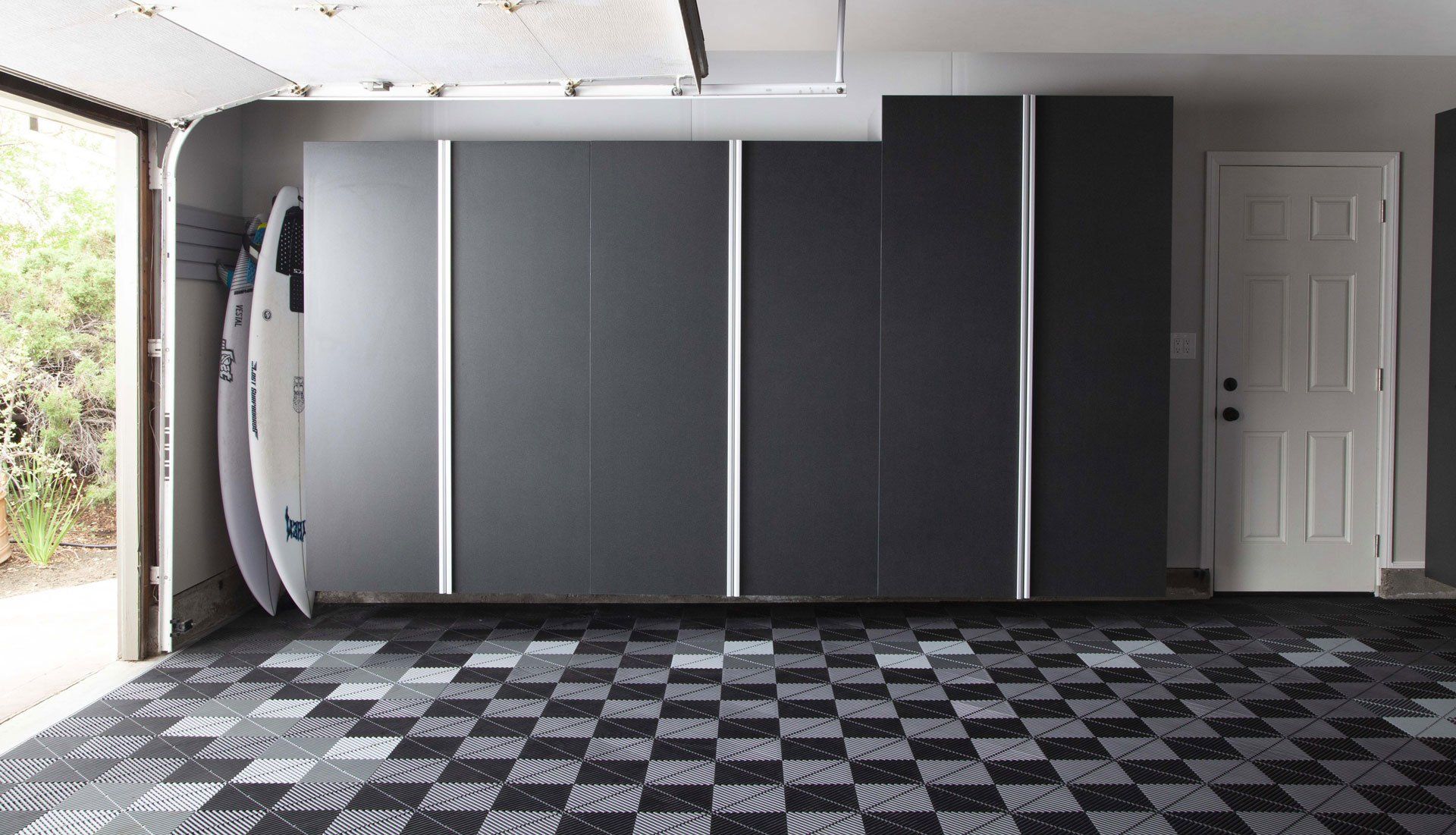 A garage with a checkered floor and a surfboard hanging on the wall.