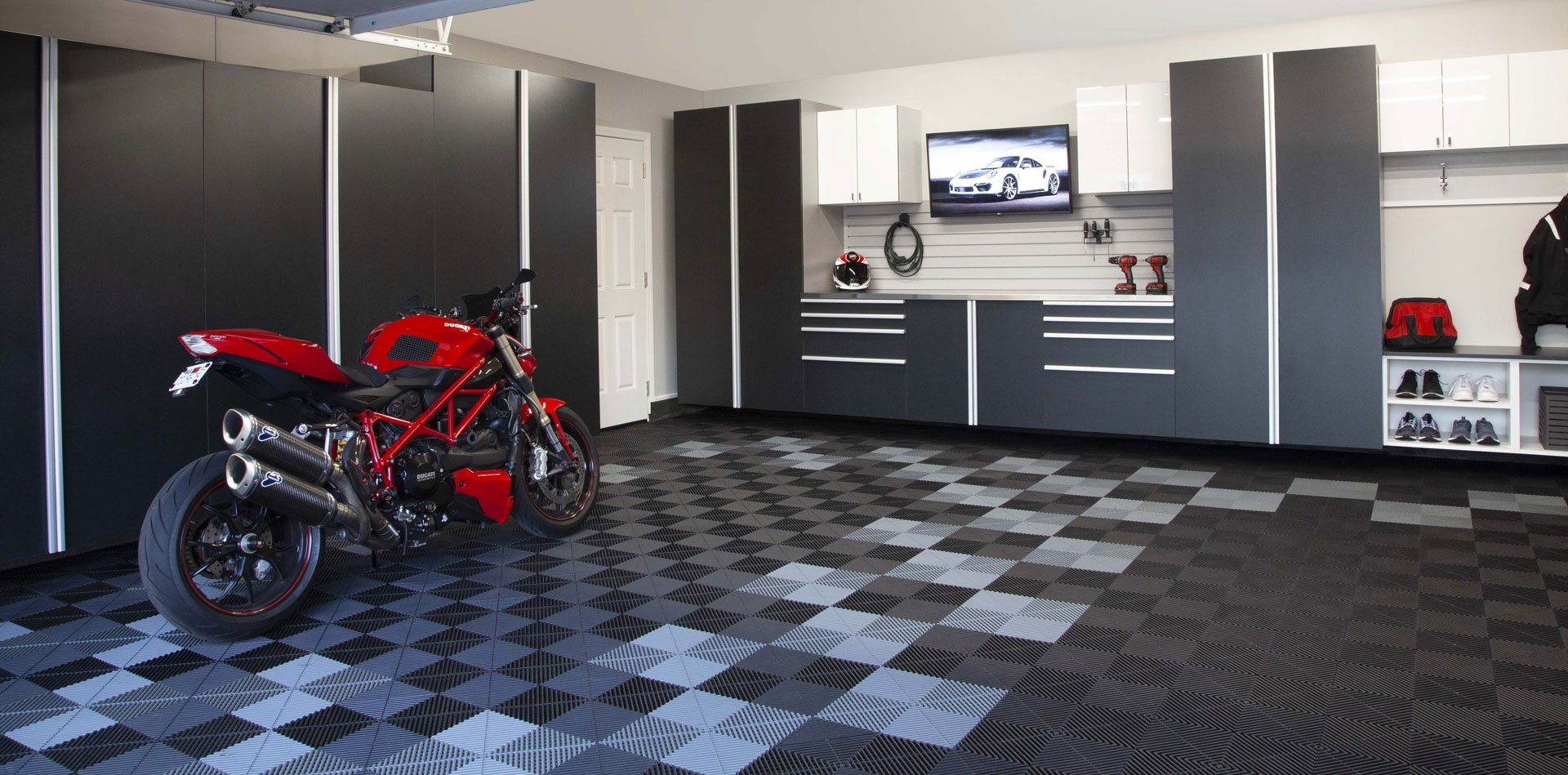 A motorcycle is parked in a garage with a checkered floor.