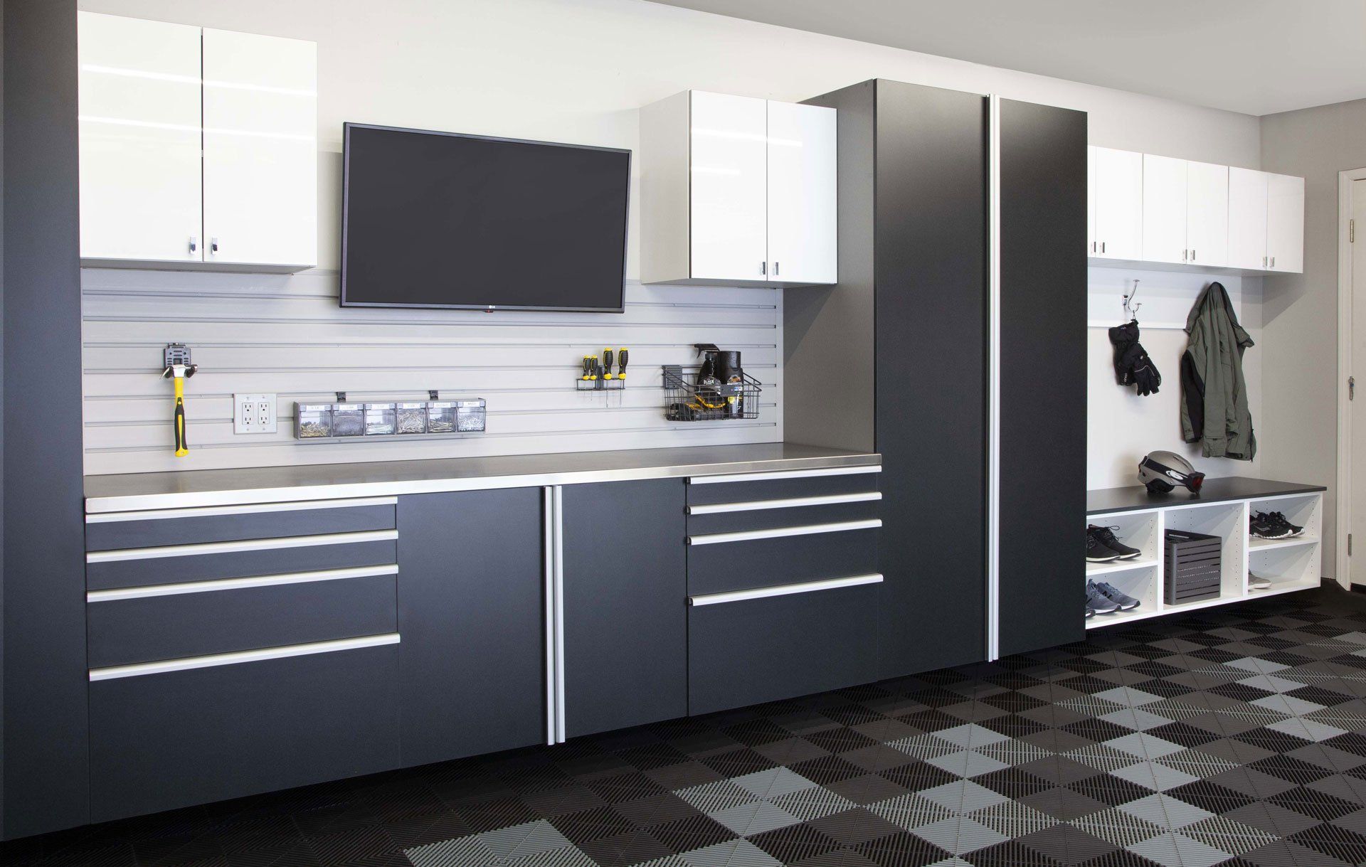 A garage with black and white cabinets and a tv on the wall.