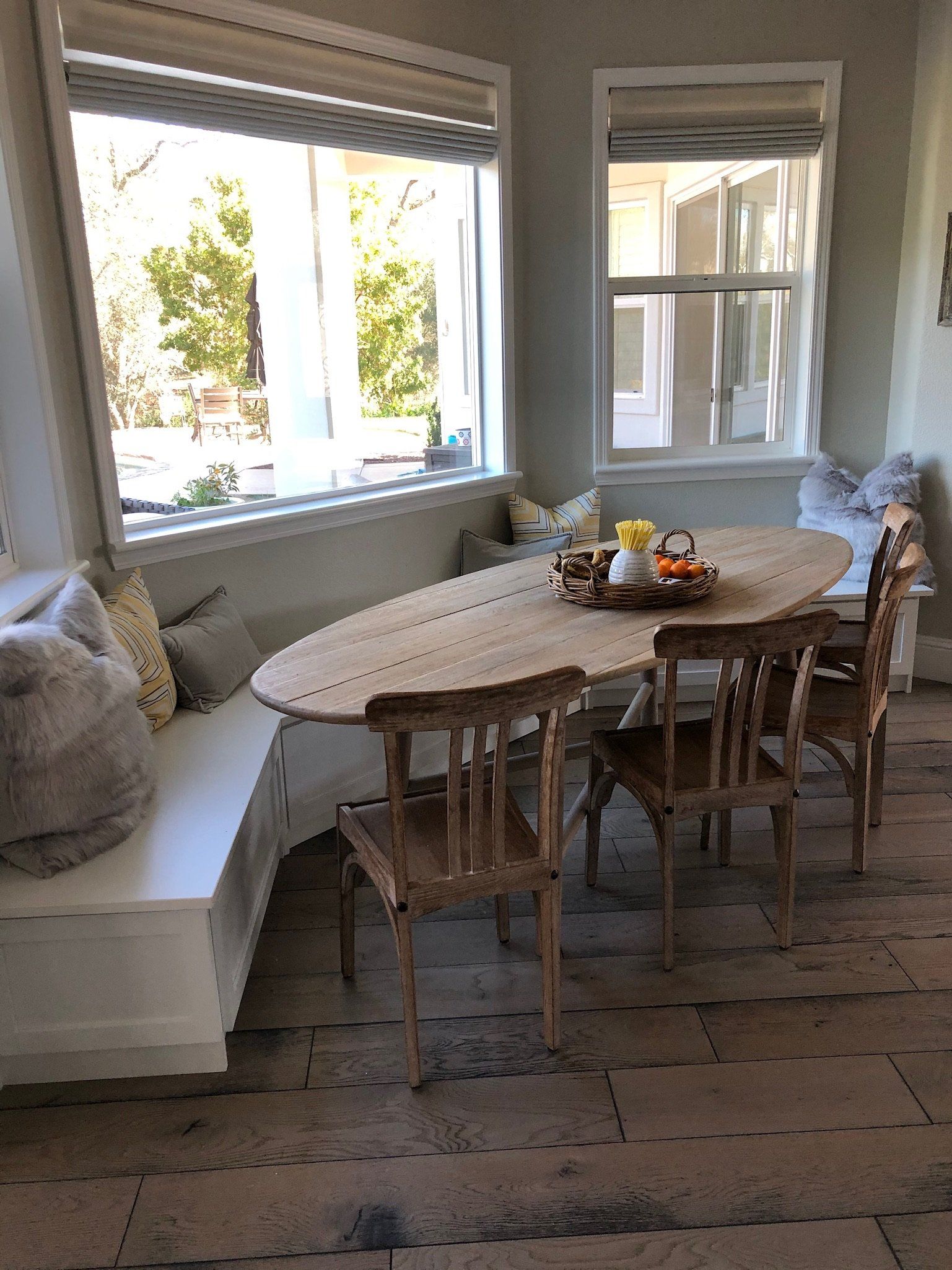 A dining room with a table and chairs in front of a window.