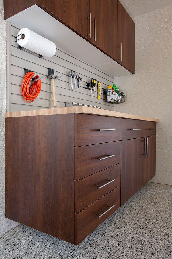 A kitchen with wooden cabinets and drawers and a paper towel holder.