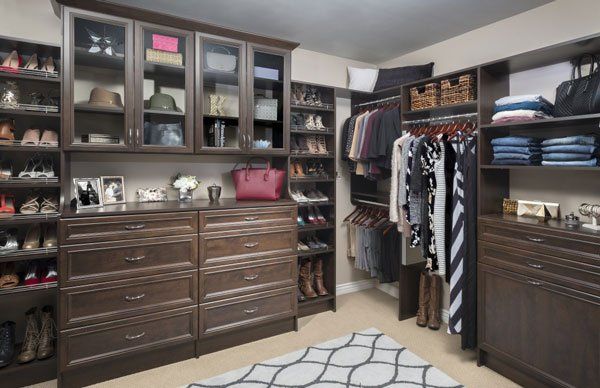A walk in closet filled with lots of clothes and shoes.