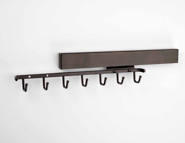 A metal shelf with hooks attached to it on a white wall.