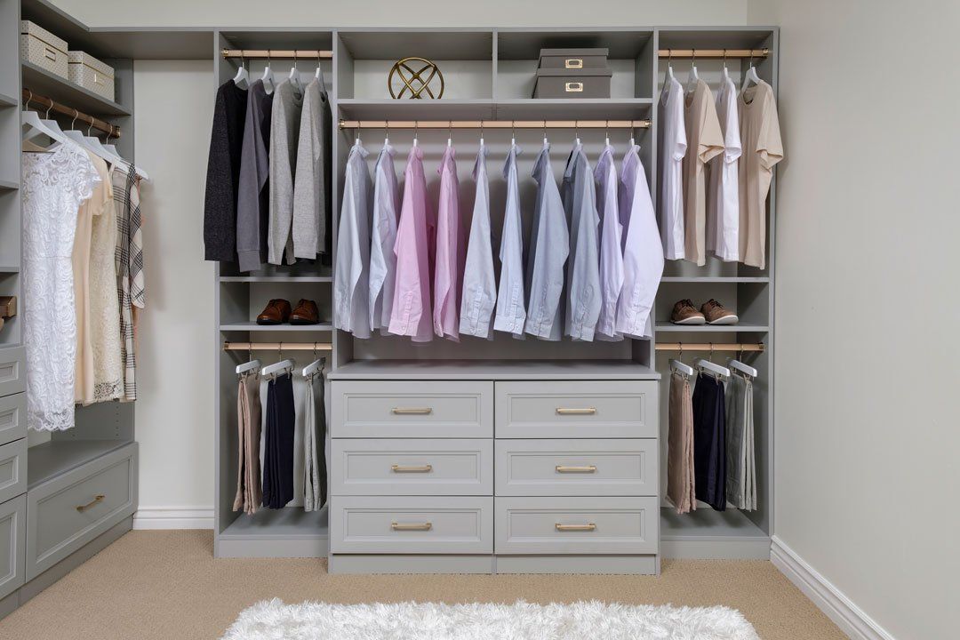 A walk in closet filled with lots of clothes and drawers.