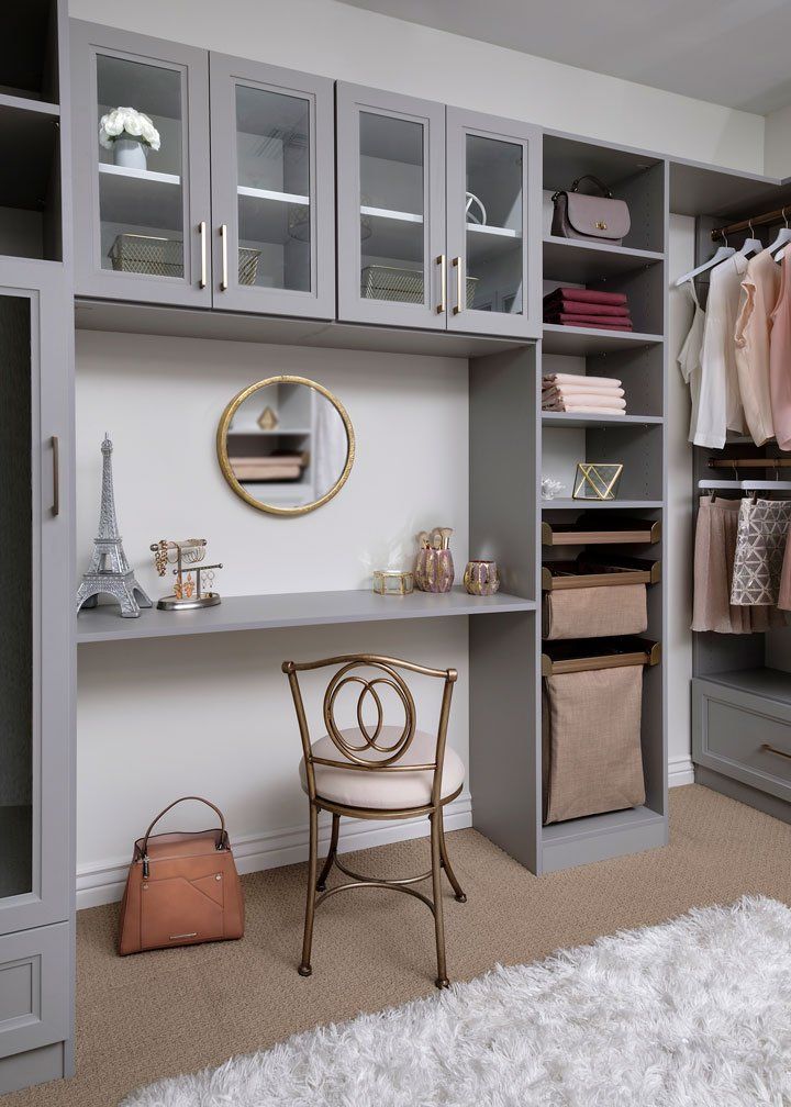 A walk in closet with a desk , chair , mirror and shelves.