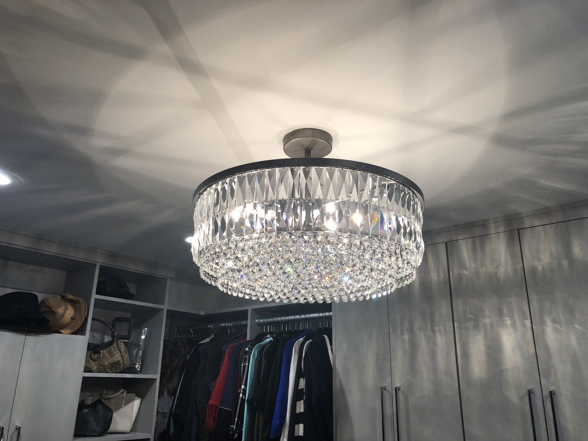 A large chandelier is hanging from the ceiling in a walk in closet.