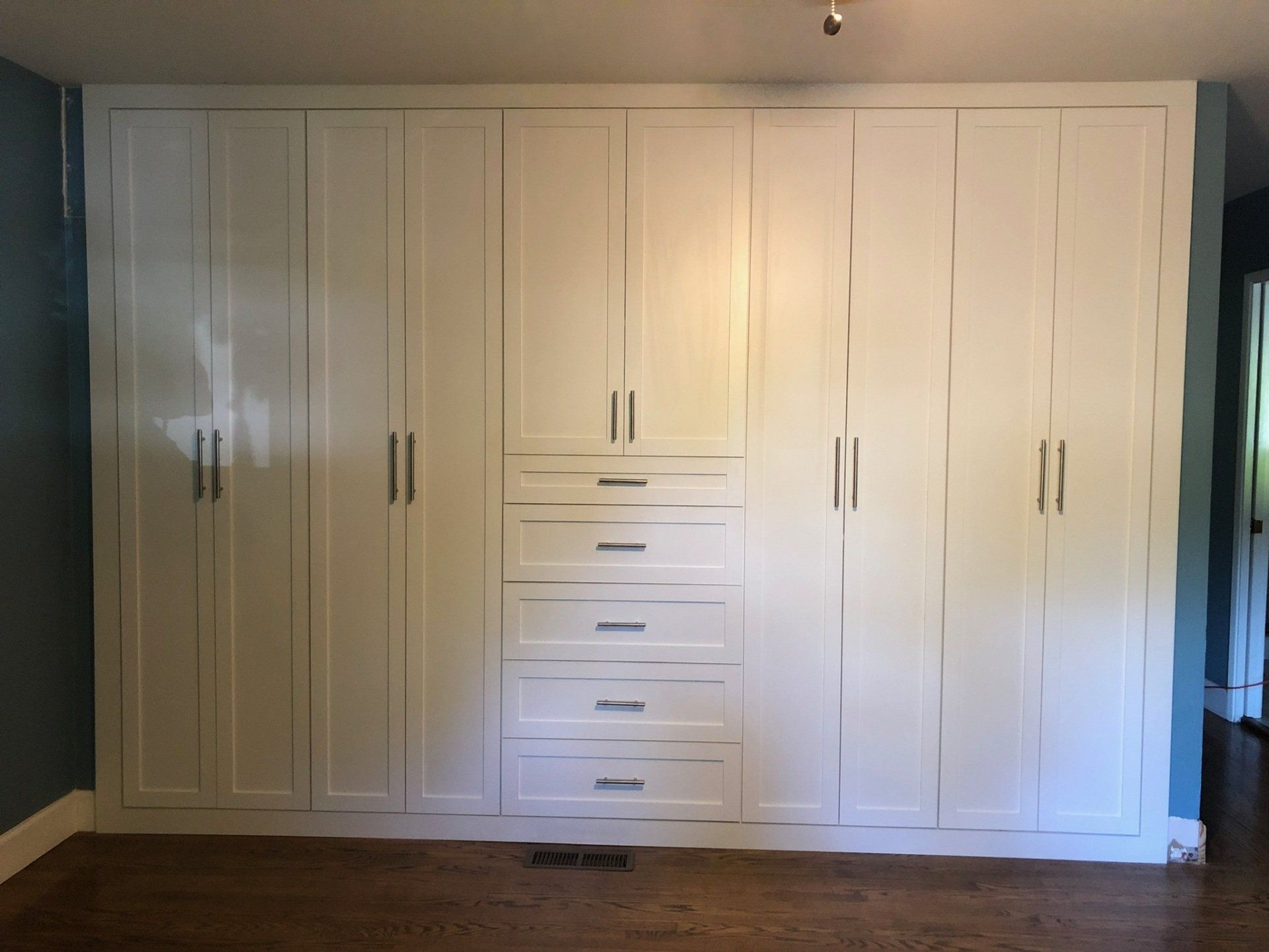 A large wall of white cabinets and drawers in a room.