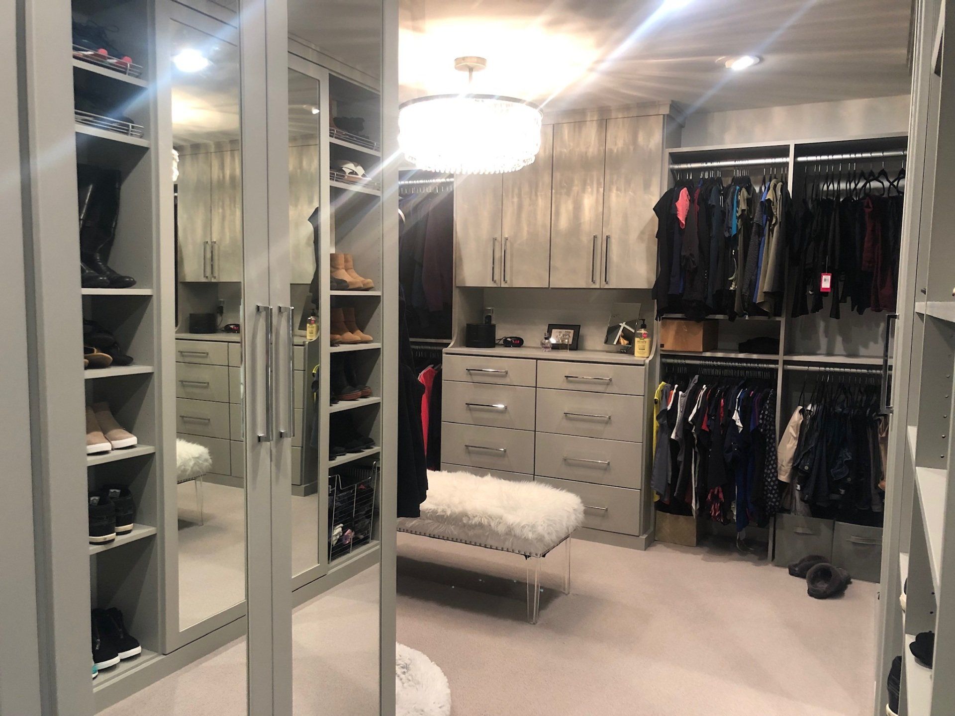 A walk in closet with lots of clothes and a bench.