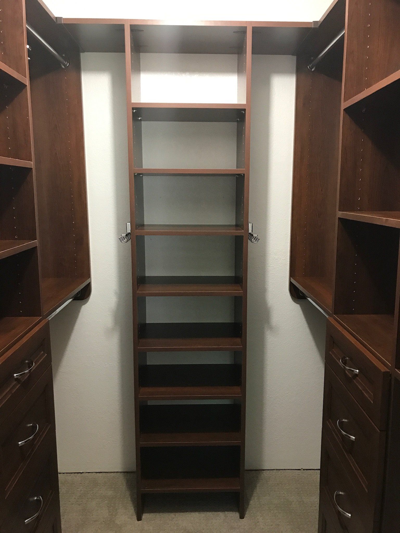 A walk in closet with lots of shelves and drawers