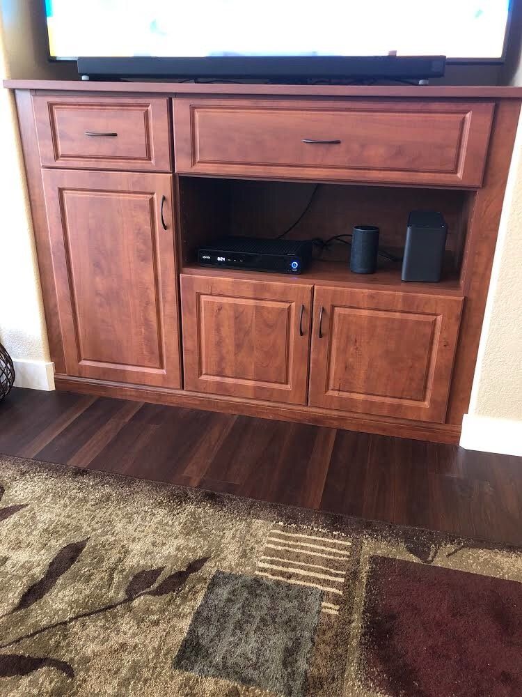 A tv is sitting on top of a wooden entertainment center in a living room.