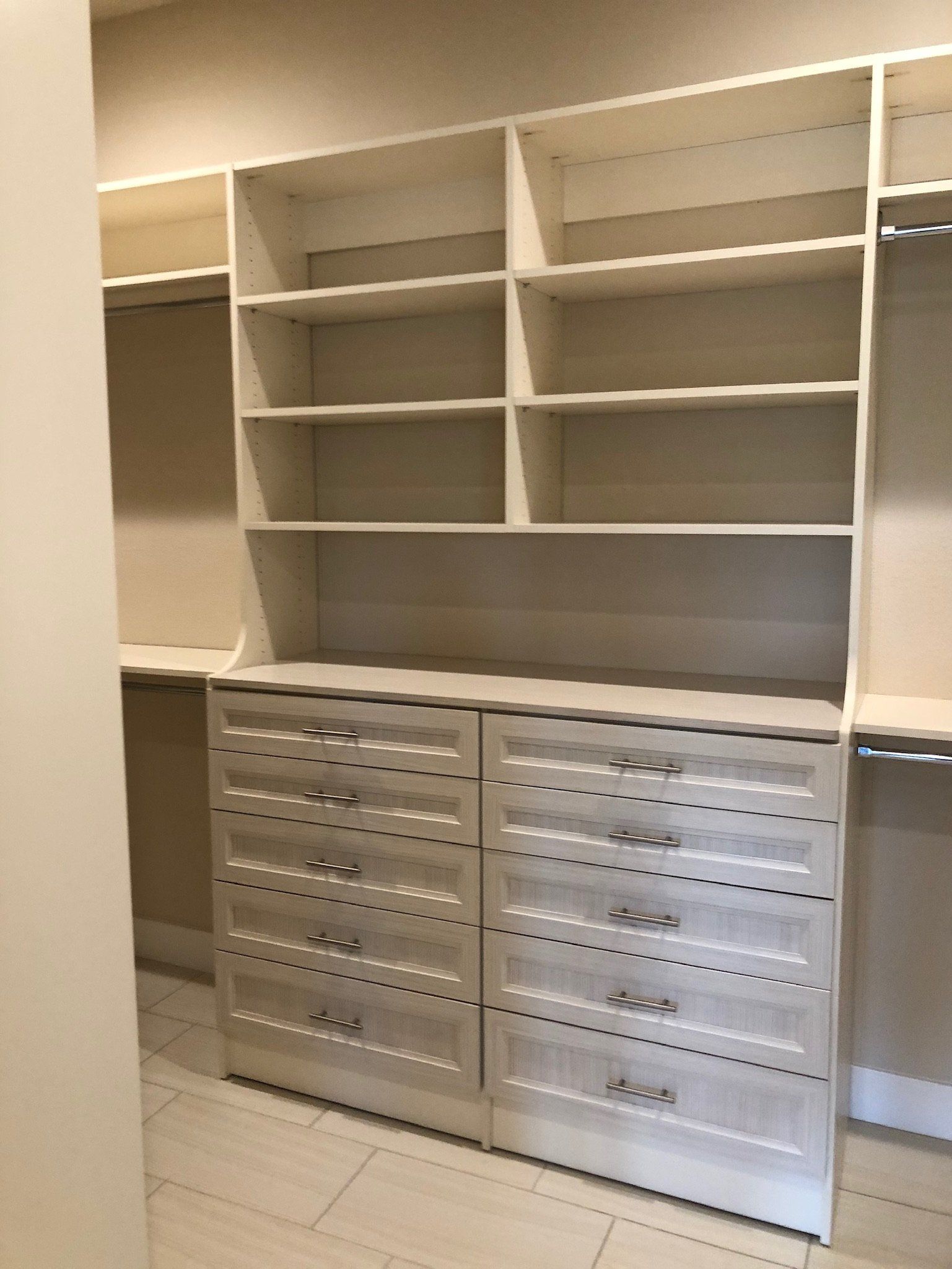 A walk in closet with lots of shelves and drawers