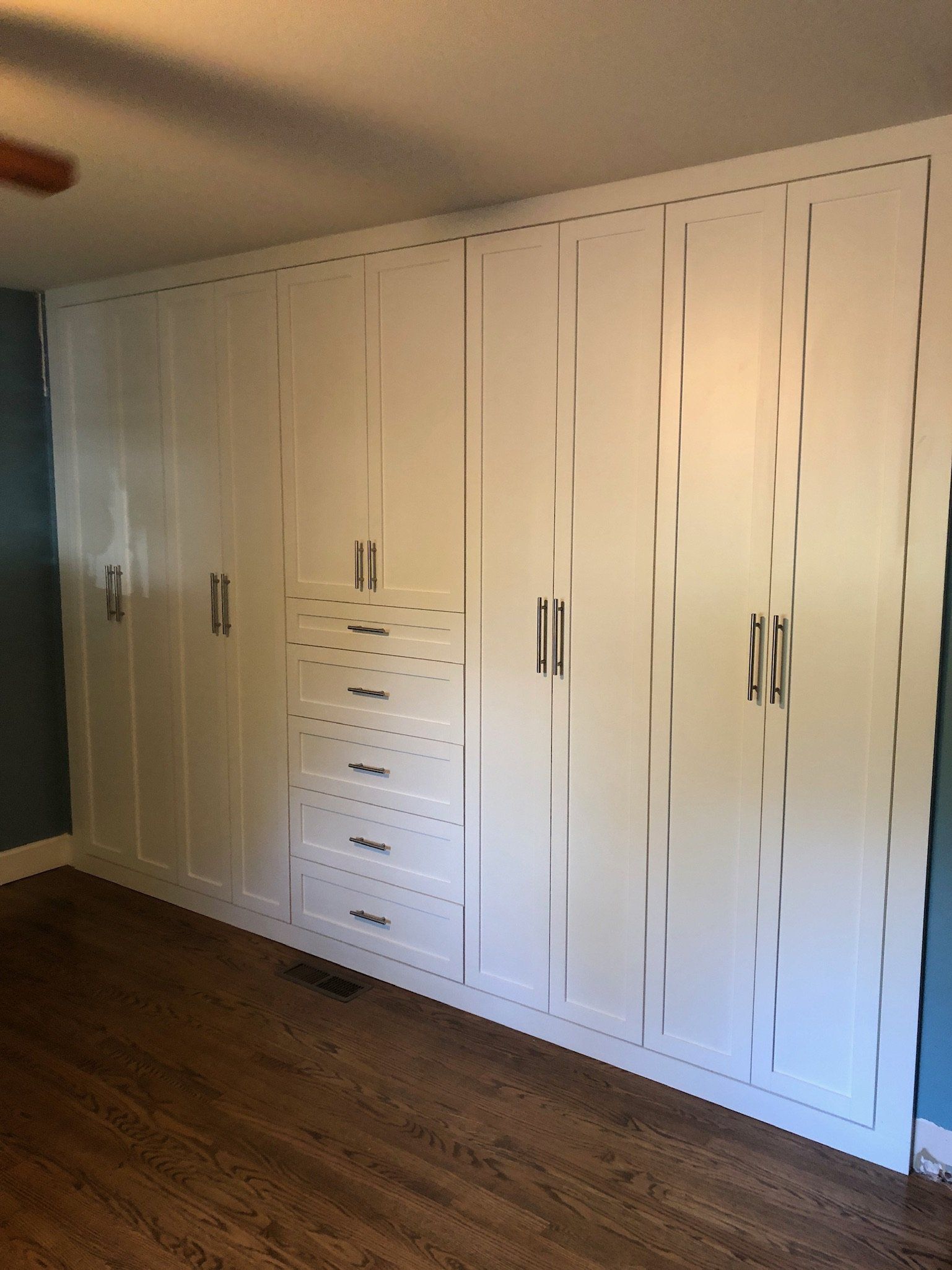 A room with a lot of white cabinets and drawers on the wall.