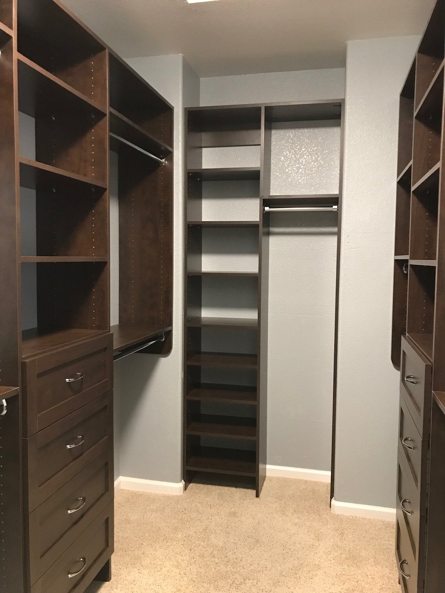 A walk in closet with lots of shelves and drawers