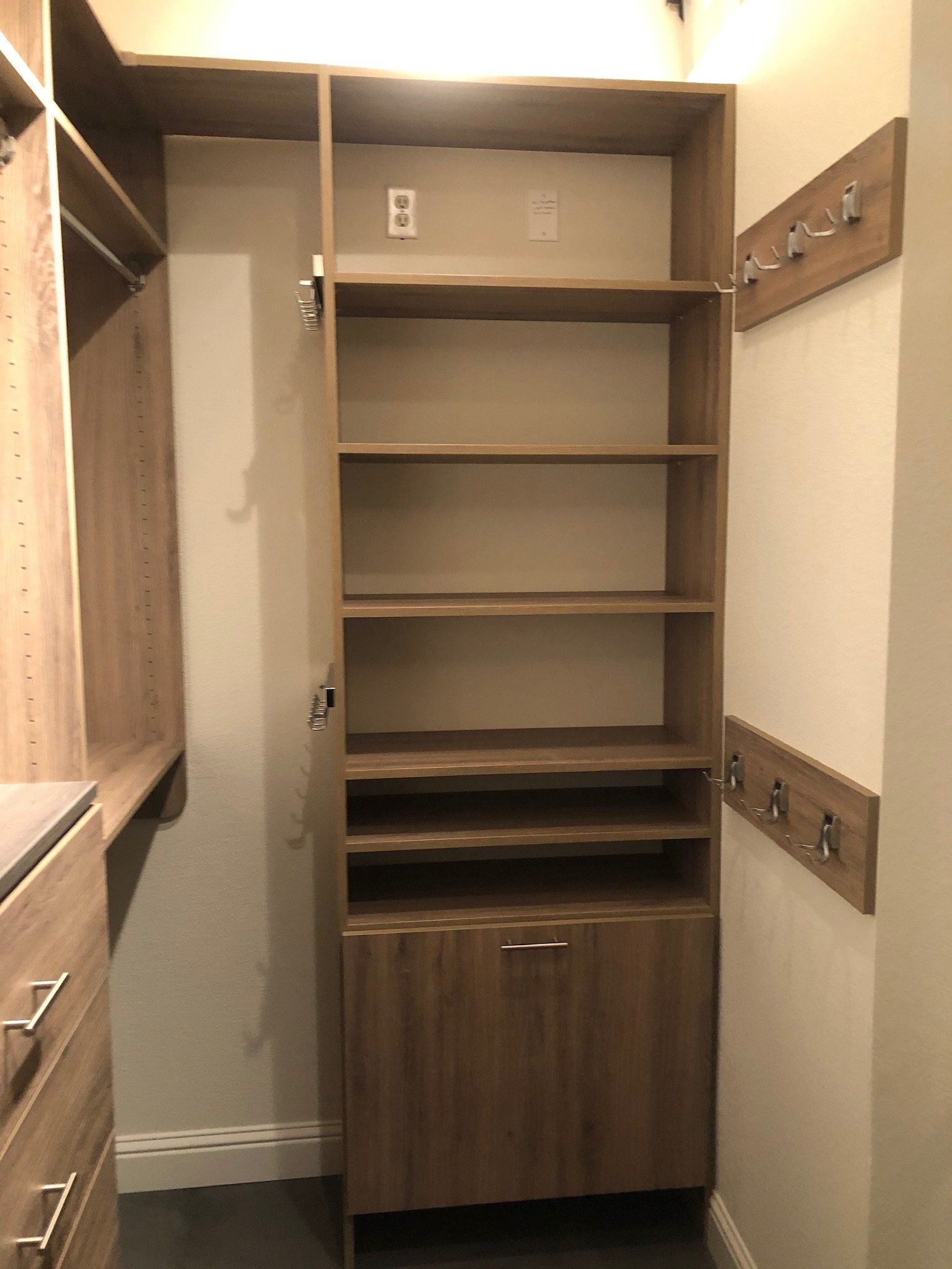 A walk in closet with lots of shelves and hooks.