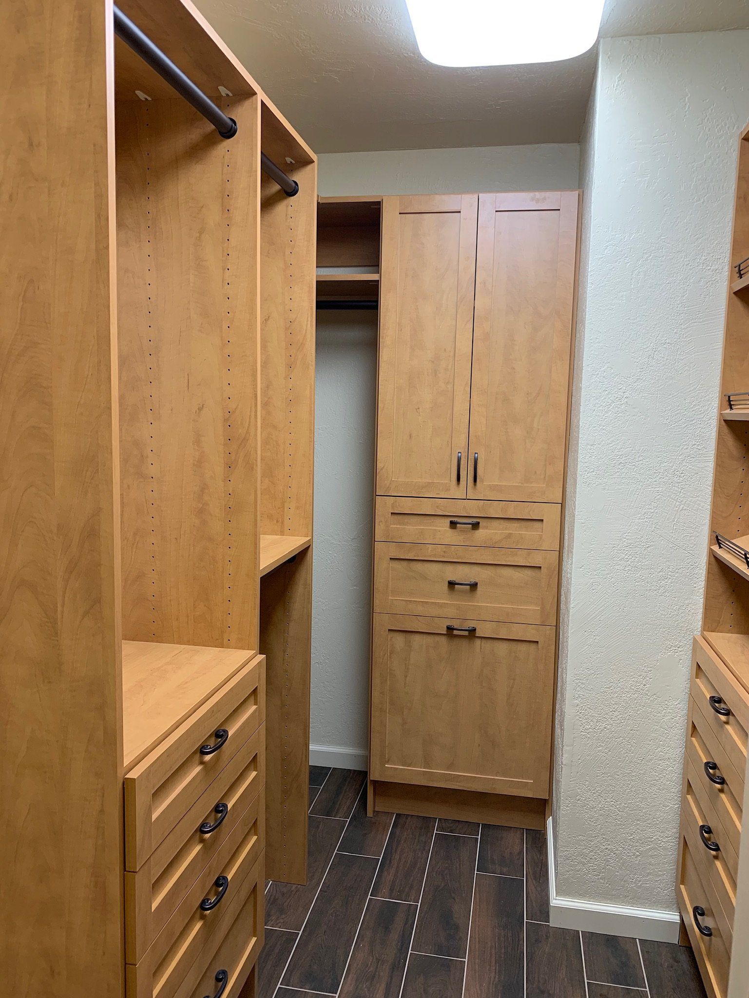A walk in closet with wooden cabinets and drawers