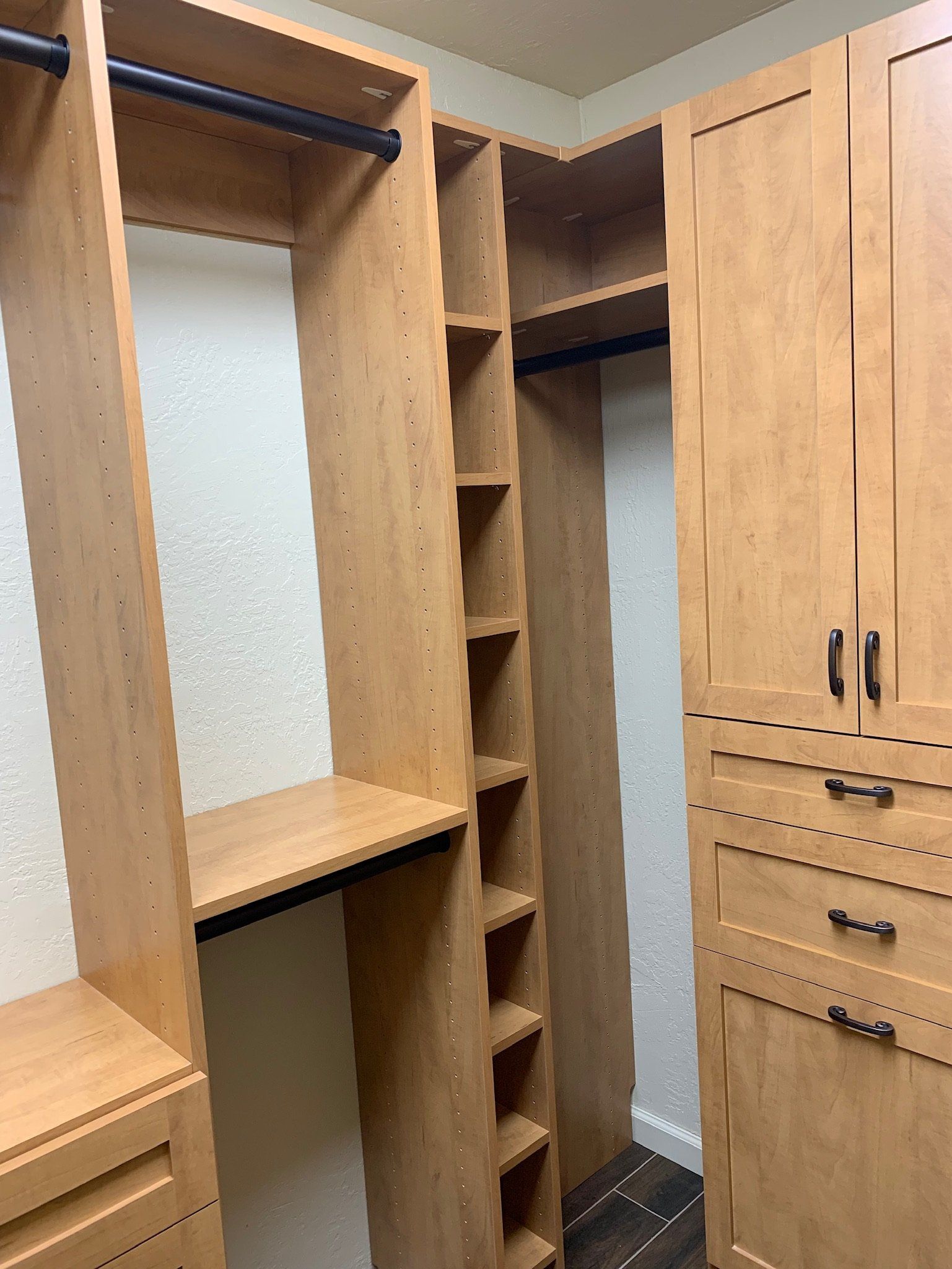 A walk in closet with lots of wooden shelves and drawers.