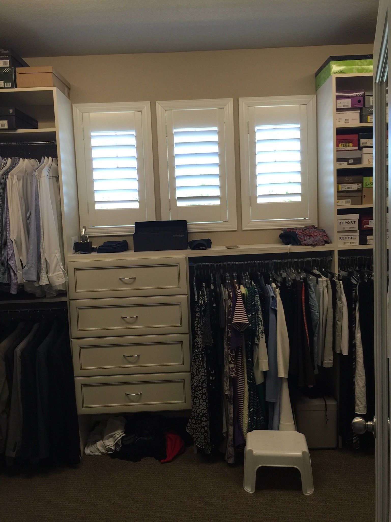 A walk in closet with lots of clothes and drawers