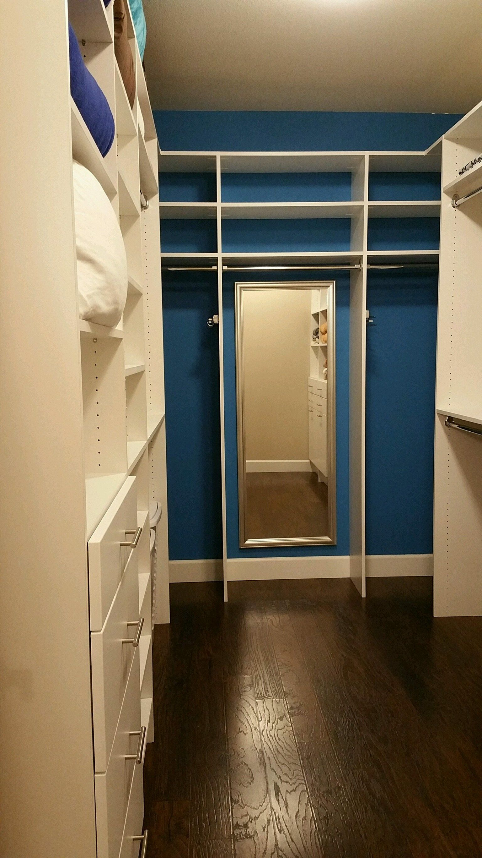 A walk in closet with blue walls and a mirror